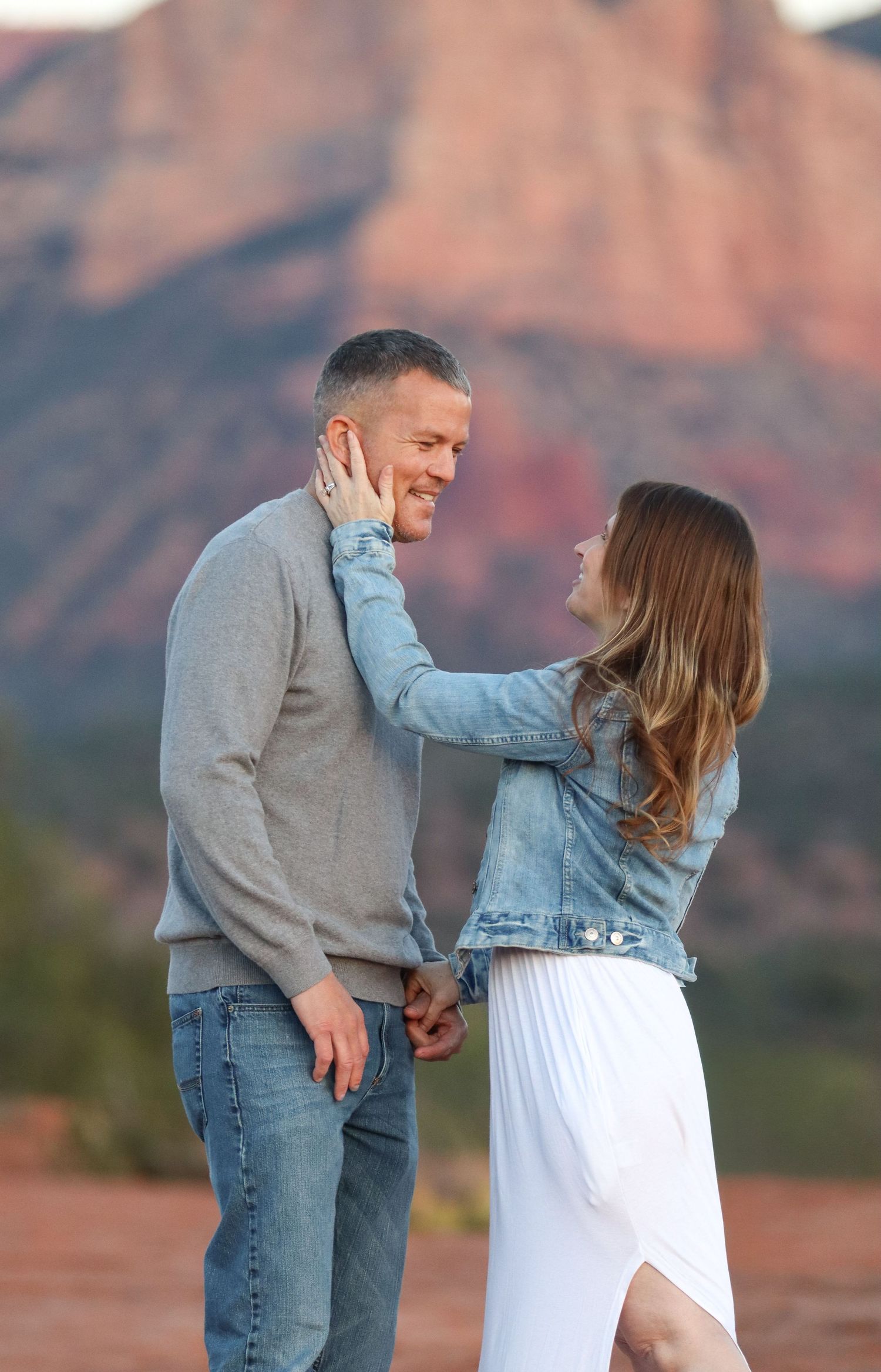 A couple shares a tender moment against the backdrop of Sedona's red rock landscape in Sedona Arizona.