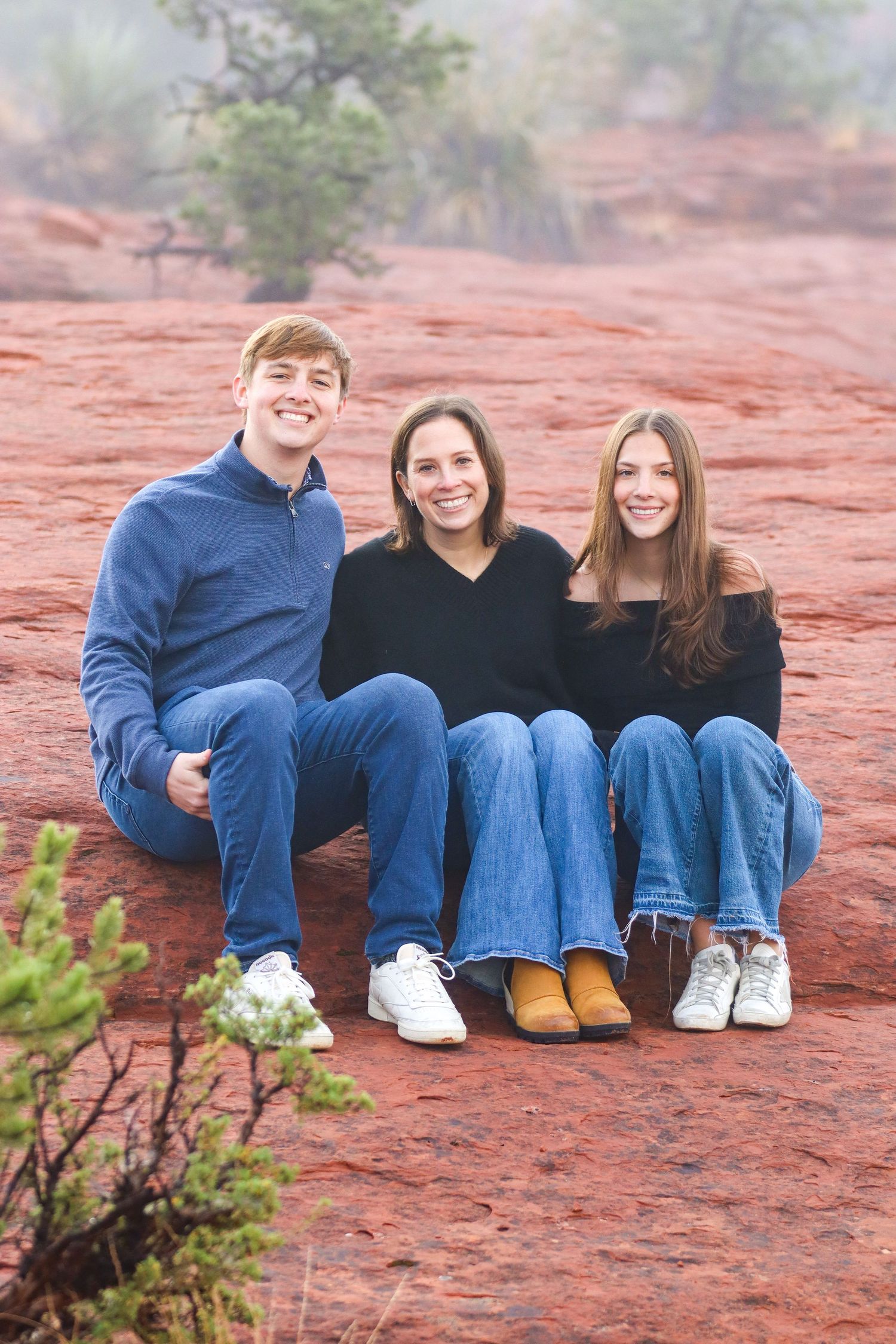 Family sitting together on red rocks wearing coordinated blue and black outfits in Sedona Arizona.