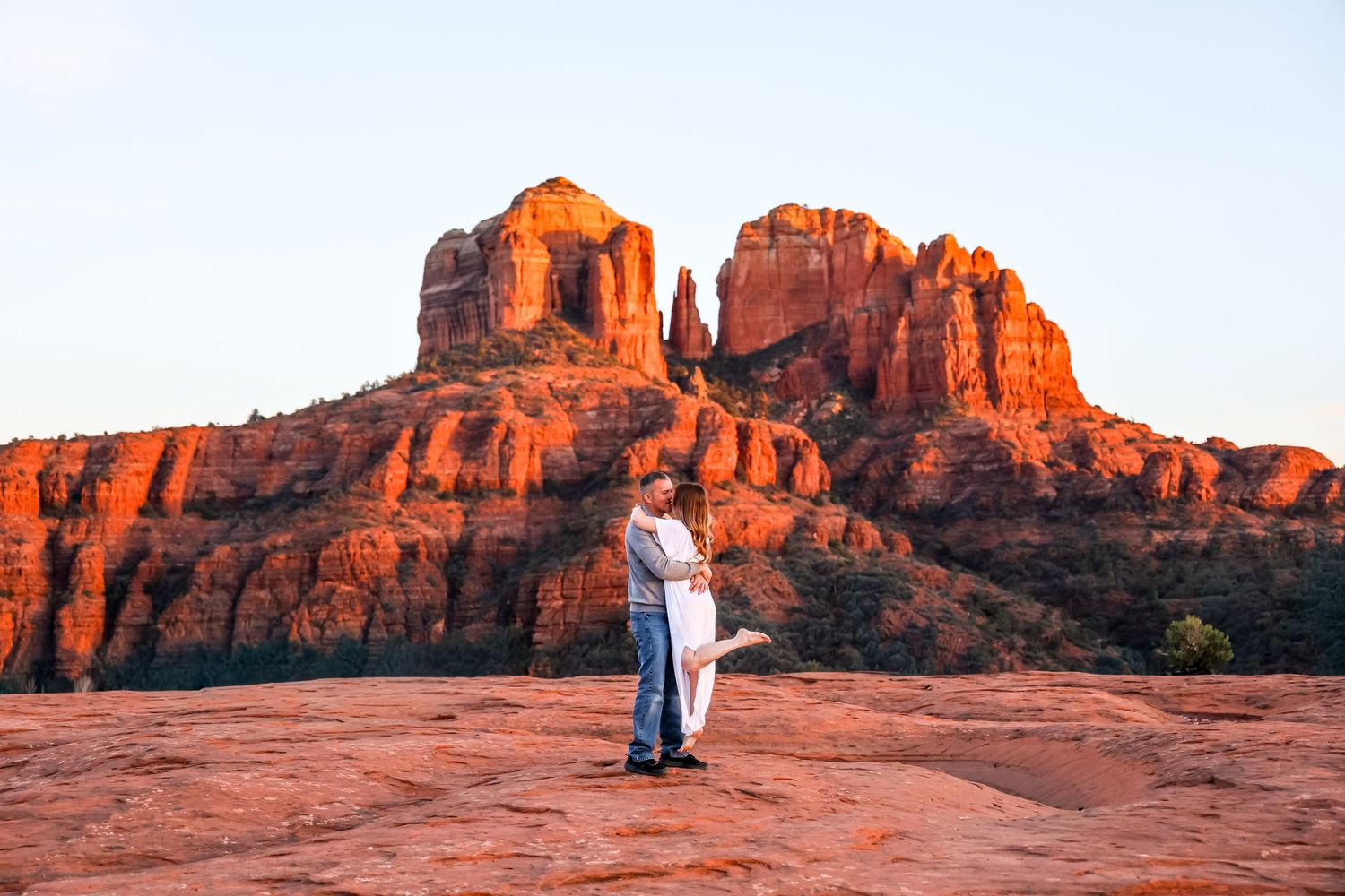 Panoramic view of red rock formations at sunset with tiny figures in the distance in Sedona Arizona at Secret Slickrock.