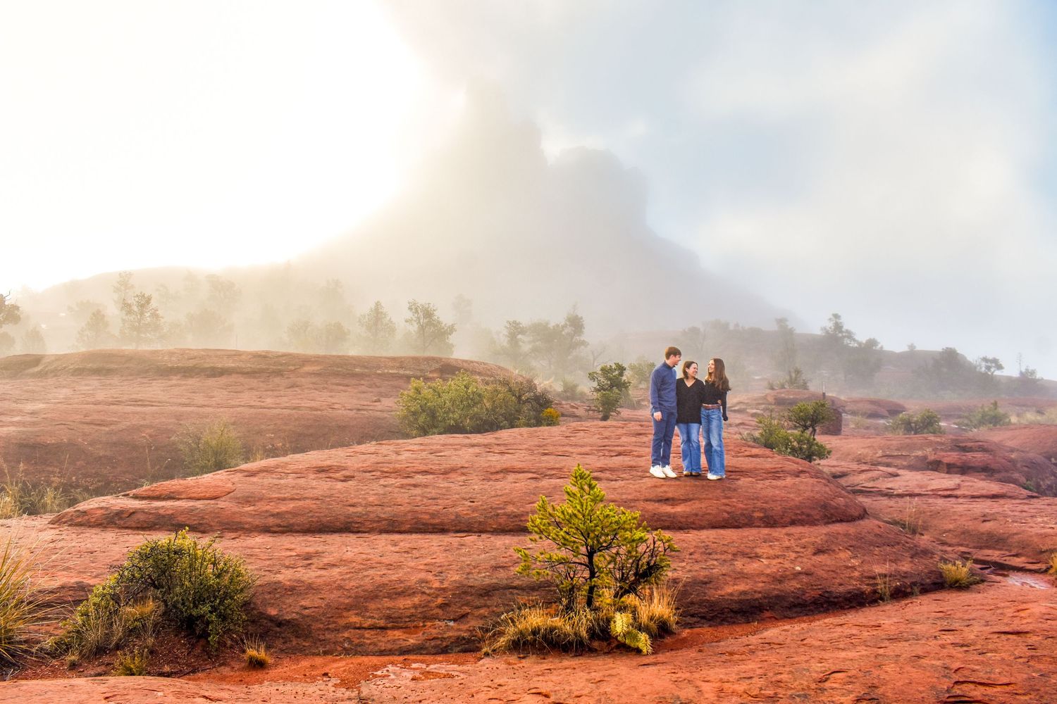 Misty morning landscape view of red rock formations with people in the distance in Sedona Arizona.