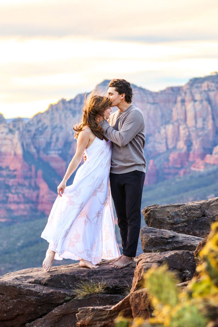 A romantic couple poses on desert rocks with stunning canyon views in Sedona Arizona.