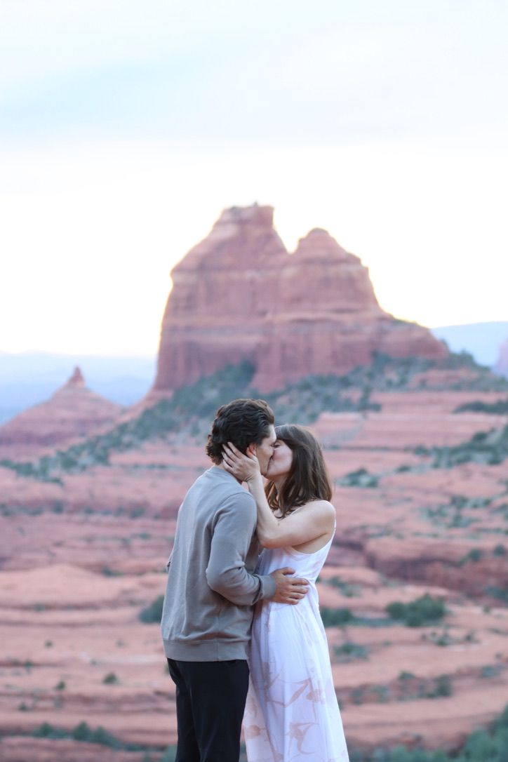 Two people embrace against the backdrop of Arizona's stunning desert landscape and red rock formations.