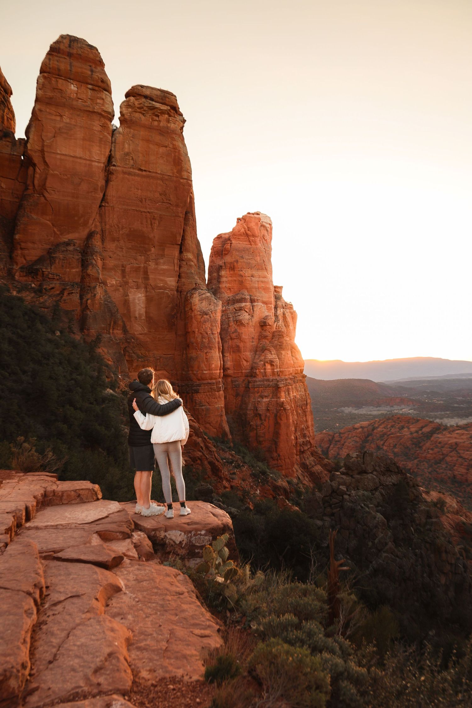 Couple admiring sunset view from Cathedral Rock formation in Sedona Arizona.