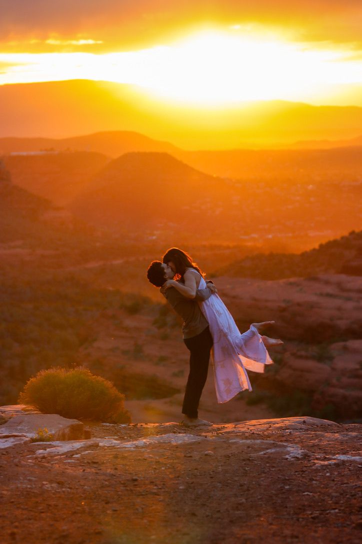 A romantic silhouette of a couple embracing against a dramatic desert sunset in Sedona Arizona.