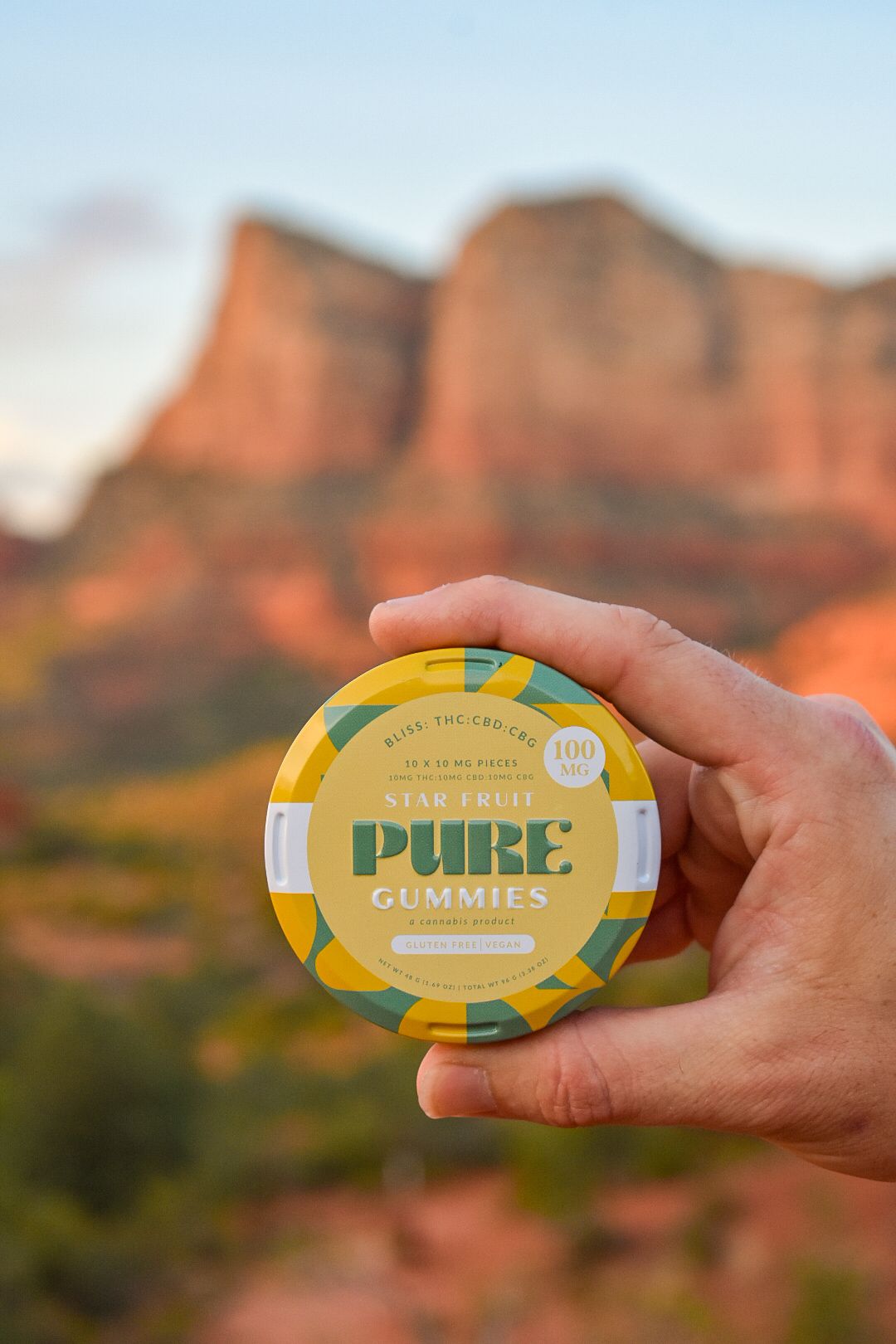 A Pure Gummies cannabis edibles container shown against a backdrop of red rock formations in Sedona, Arizona.