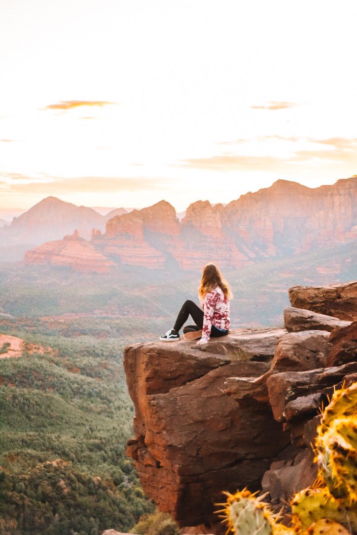 A dramatic desert overlook with red cliffs and mountains stretching into the distance at sunset in Sedona Arizona.
