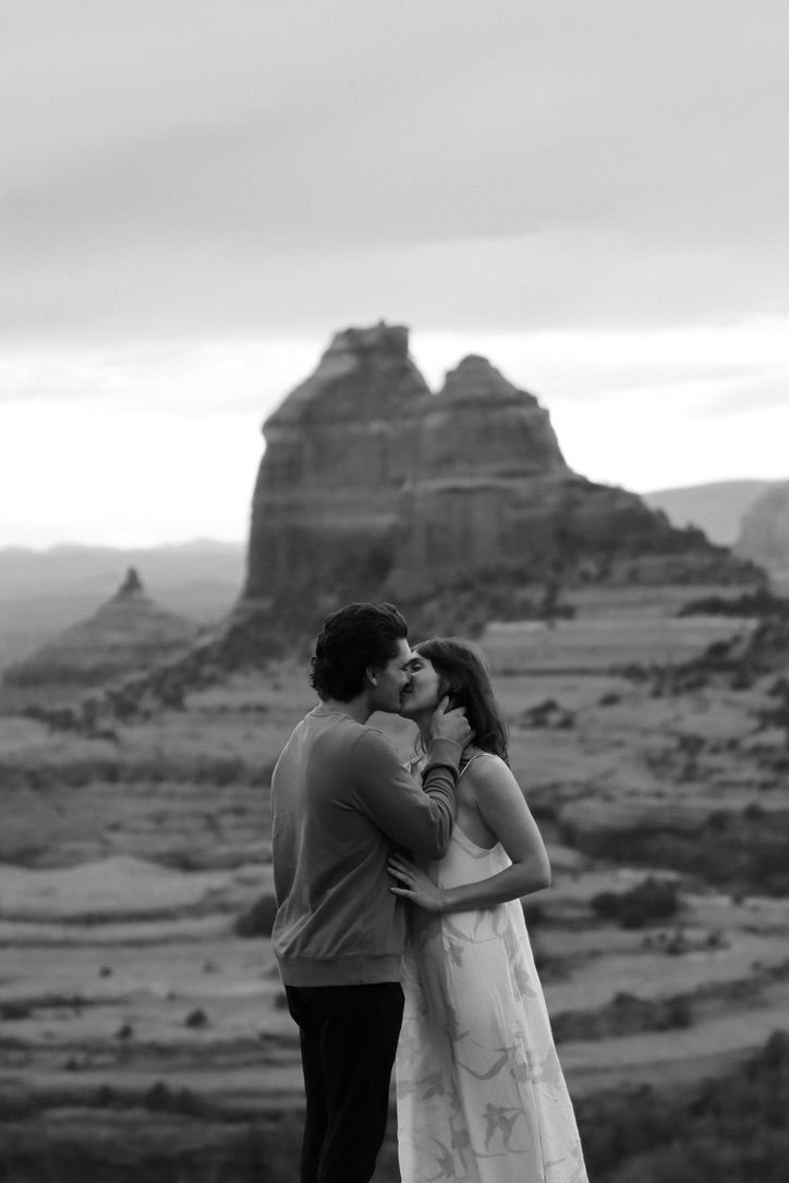 A black and white photo captures a romantic moment against dramatic desert rock formations in Sedona Arizona.