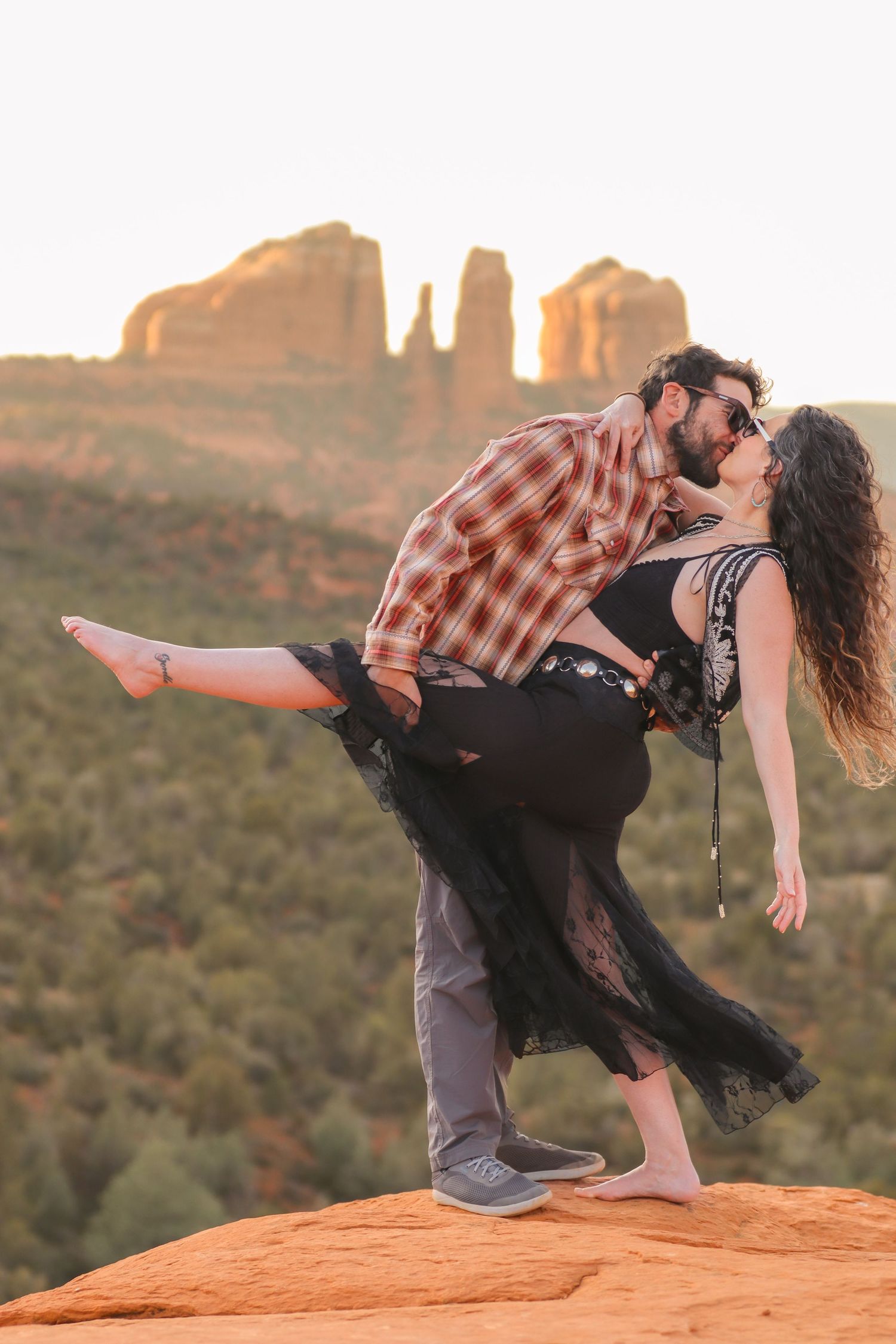 Dramatic dance dip pose on red rock formation at sunset in Sedona Arizona.