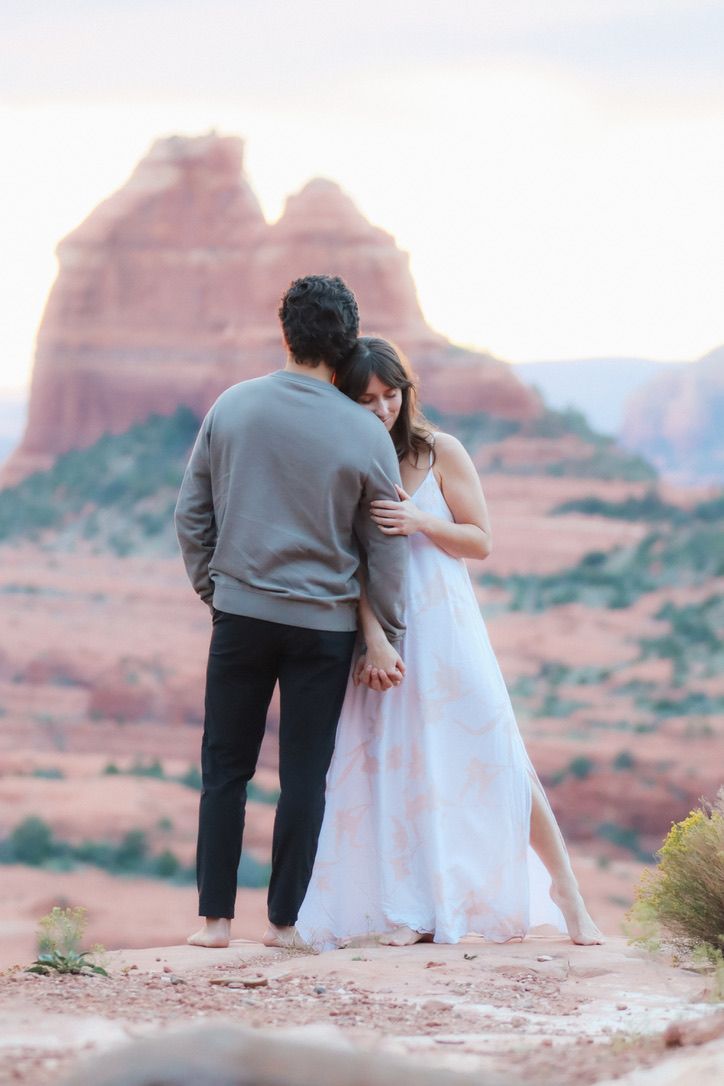 Two people share an intimate moment on desert rocks during sunset in Sedona Arizona.