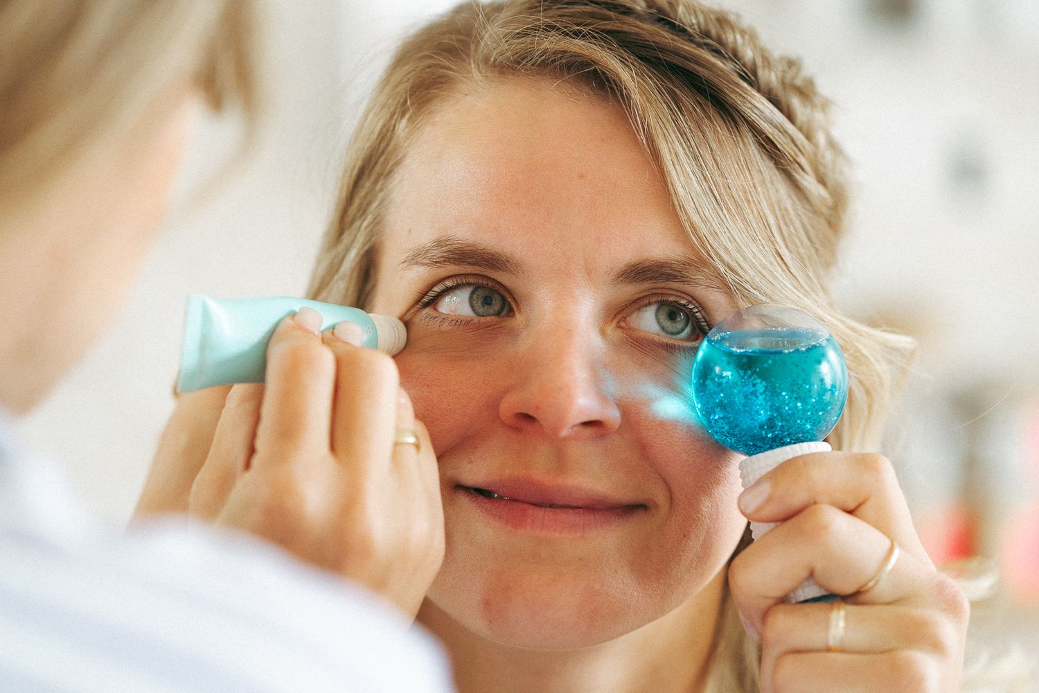 Woman applying blue gel eye patches under her eyes for skincare treatment and rejuvenation.