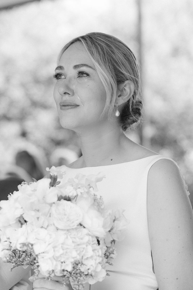 Eine emotionale Braut in einem weißen Hochzeitskleid hat Tränen in den Augen während ihrer Outdoortrauung in Siegen.