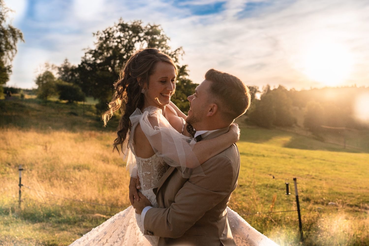Ein Hochzeitspaar liegt sich während des Sonnenuntergangs bei einer Hochzeit im Sauerland im Gute Ahe im Arm.