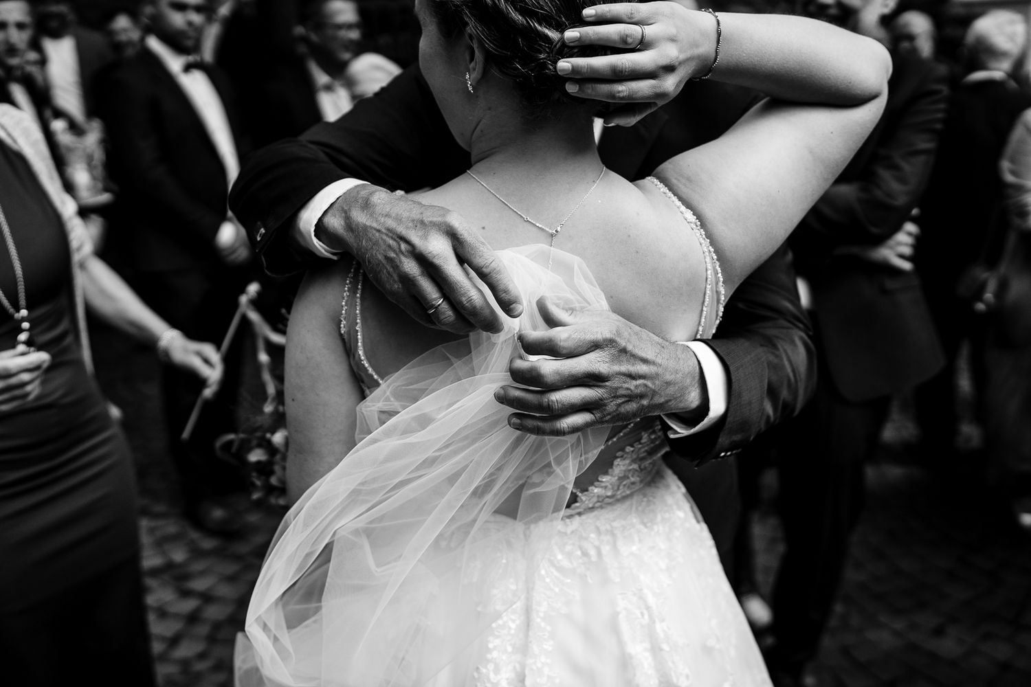 Black and white photo of a bride and groom sharing an emotional embrace at their wedding reception.