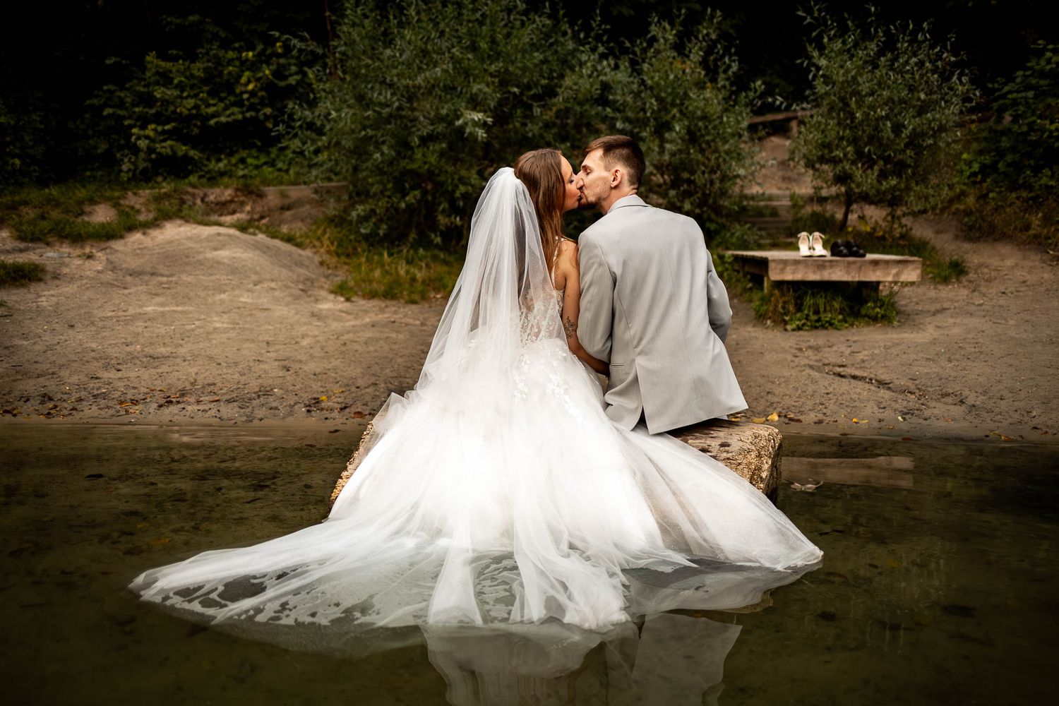 Wedding couple sitting by a peaceful lake surrounded by nature.