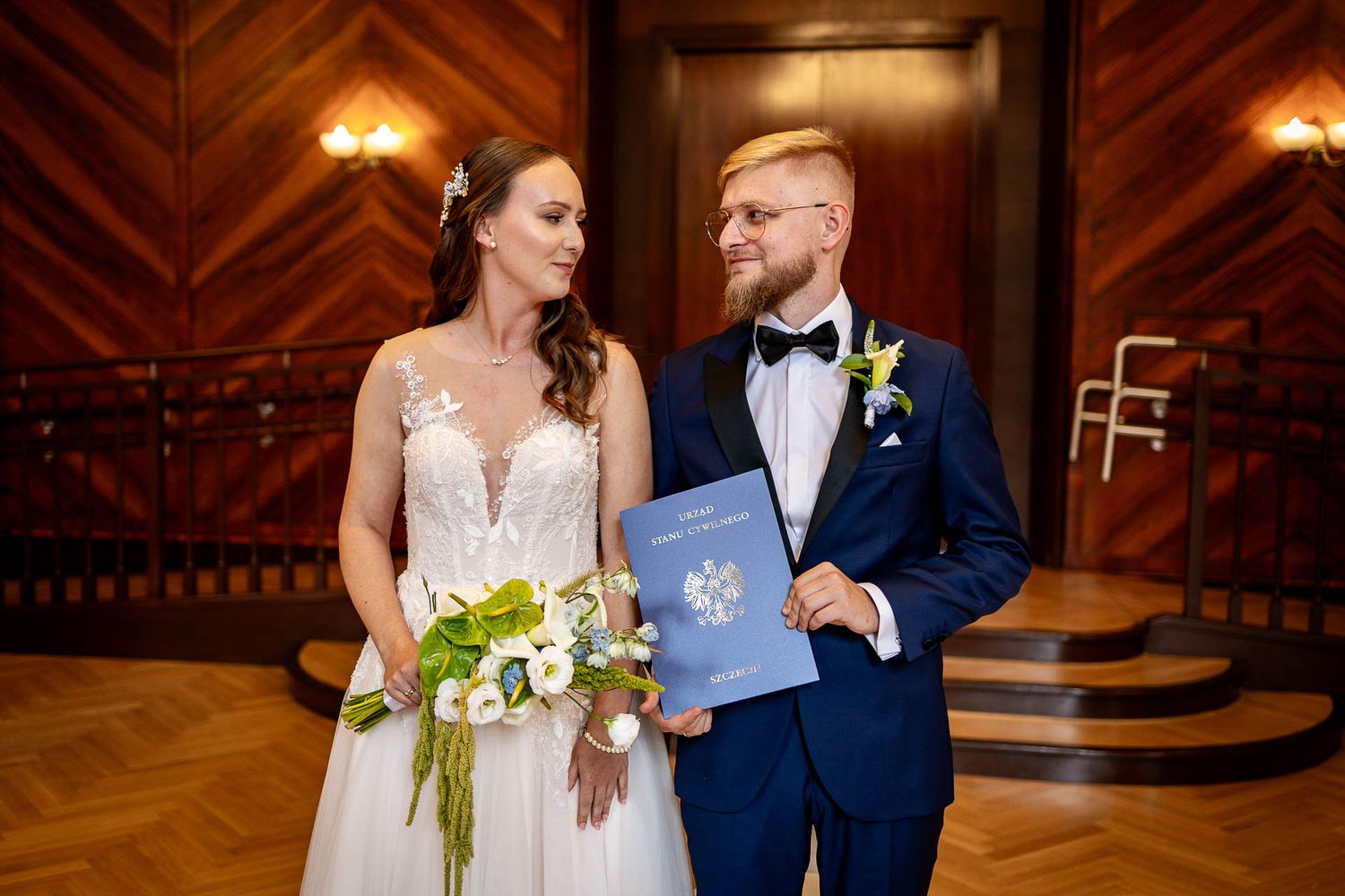 Couple dancing together in an elegant ballroom with wooden chevron floors.