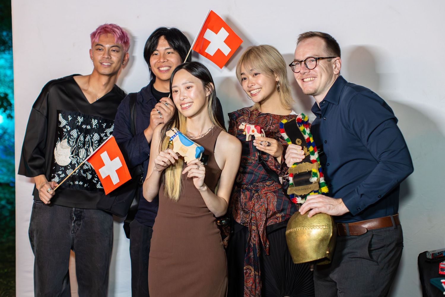 A group of people posing with Swiss flags at a celebratory event.
