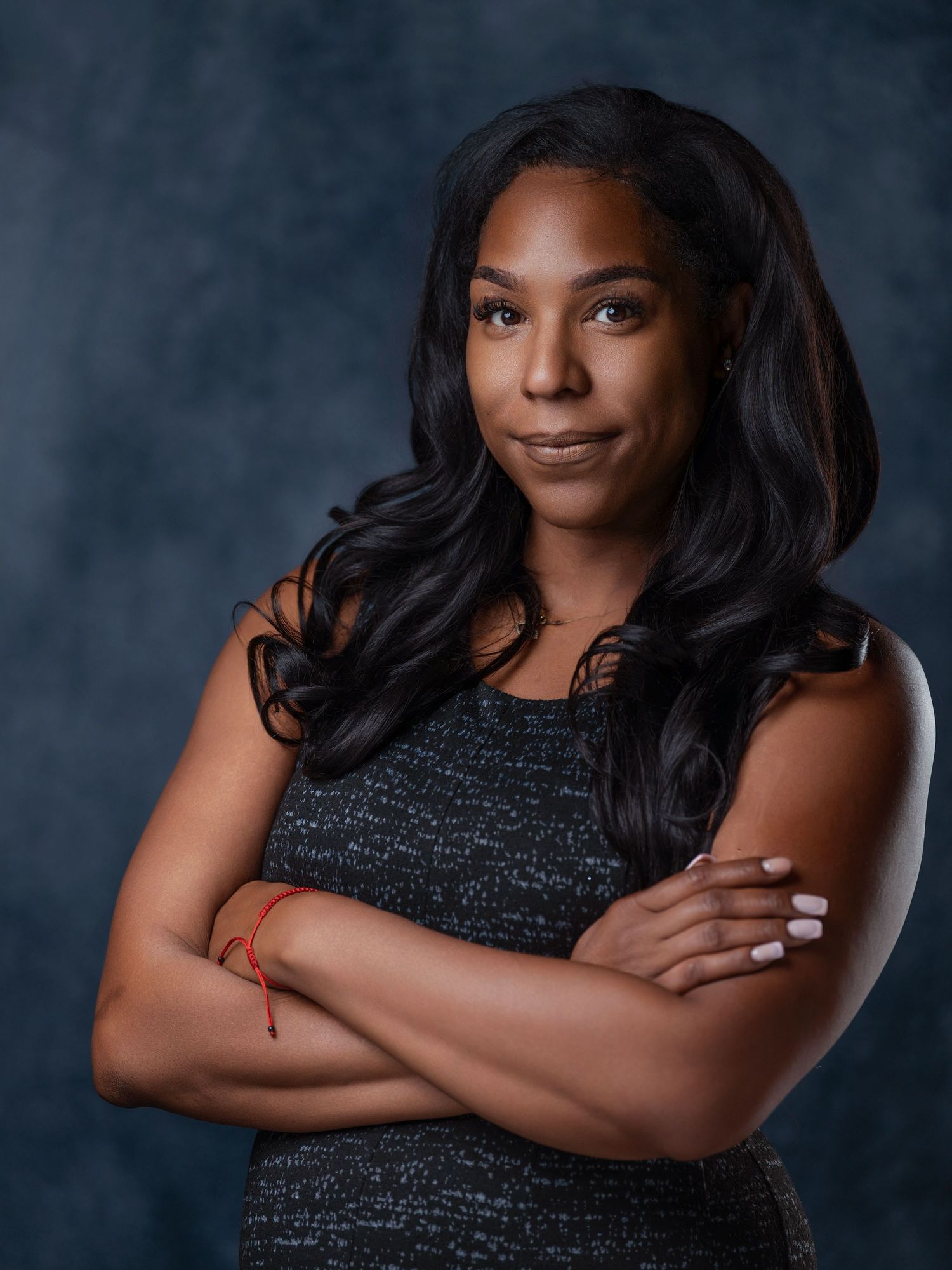 Professional studio portrait of someone wearing a black sleeveless top against a dark background with dramatic lighting.