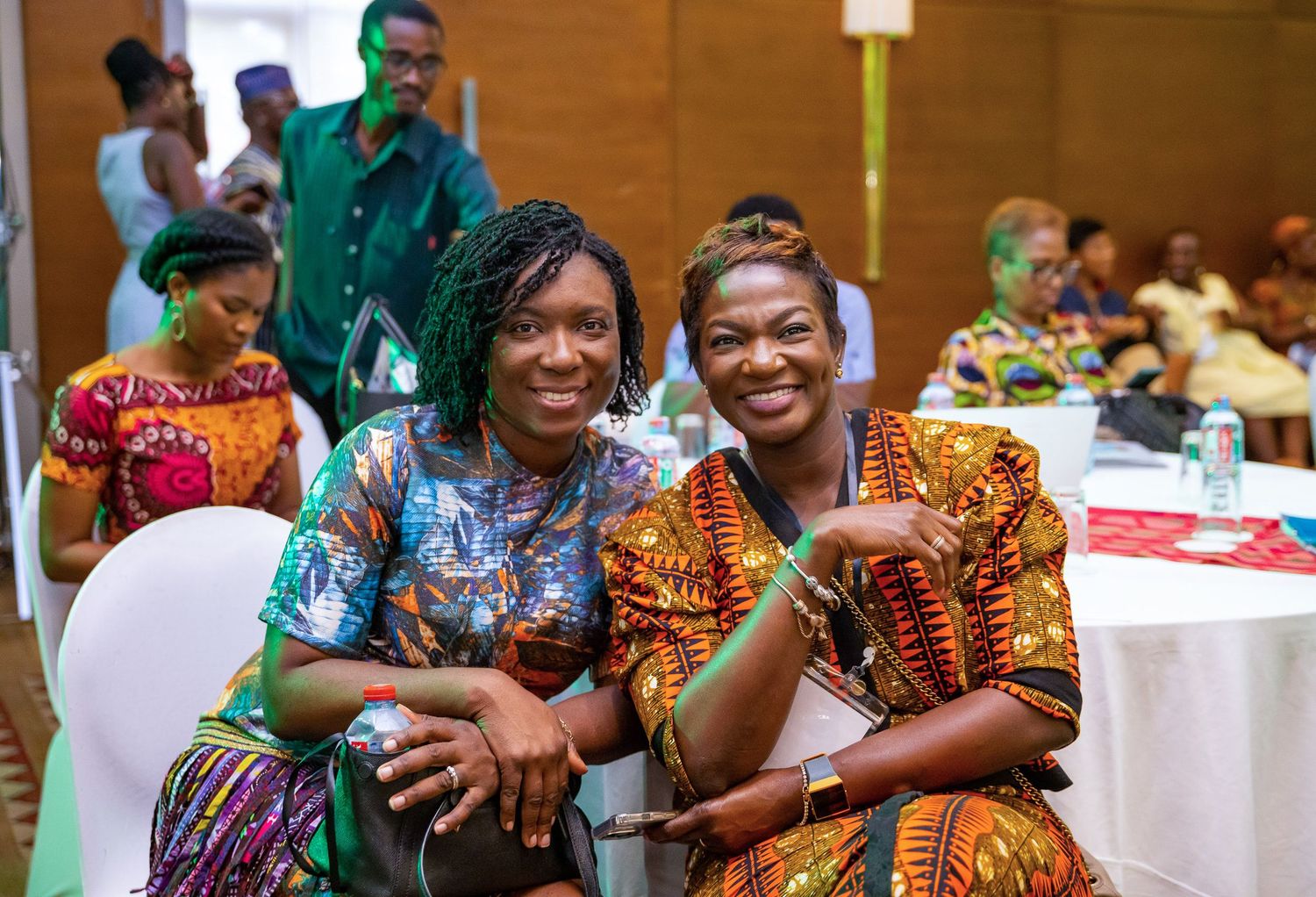 Conference attendees in colorful traditional African attire networking and socializing at a professional event.
