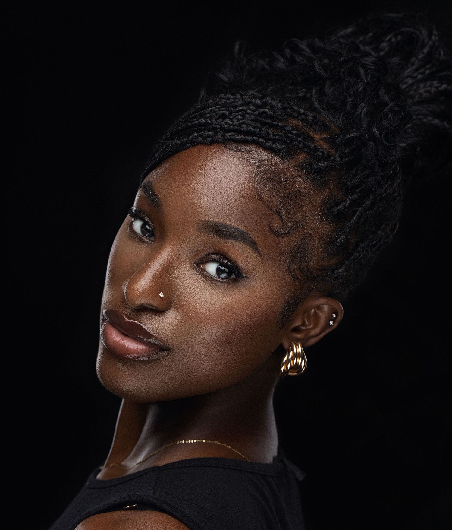 Dramatic close-up beauty portraits with gold jewelry against a black background.