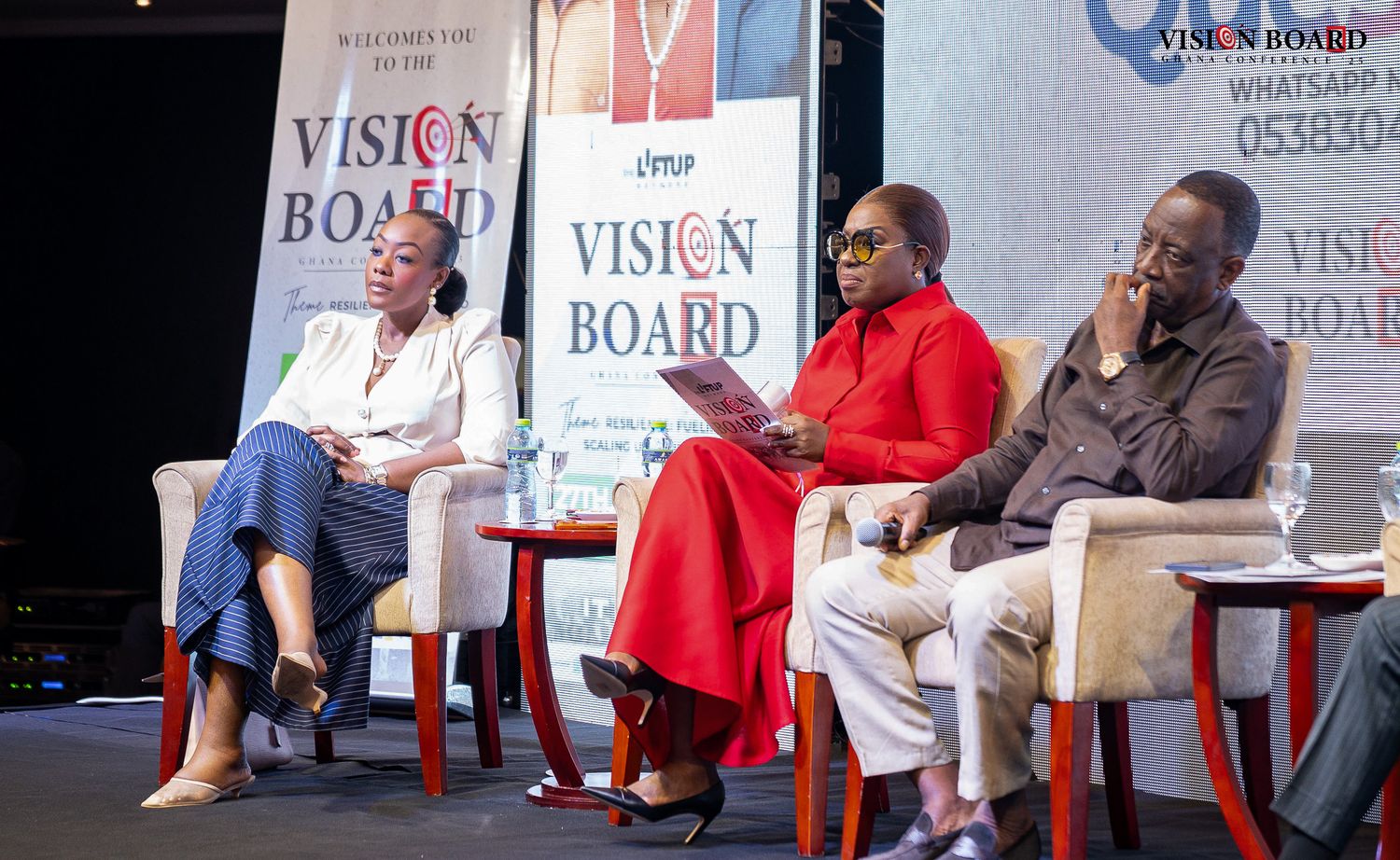 Panel discussion setup with speakers seated in chairs on stage at professional conference.