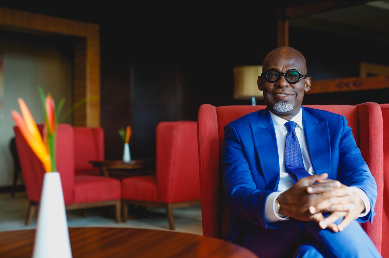 Professional in a blue suit jacket sits in a red chair at an upscale venue.