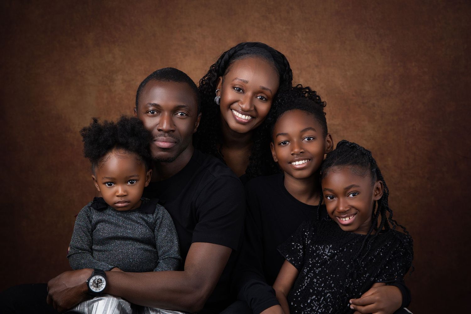 A collage of heartwarming family portraits with matching black outfits against a dark brown backdrop.