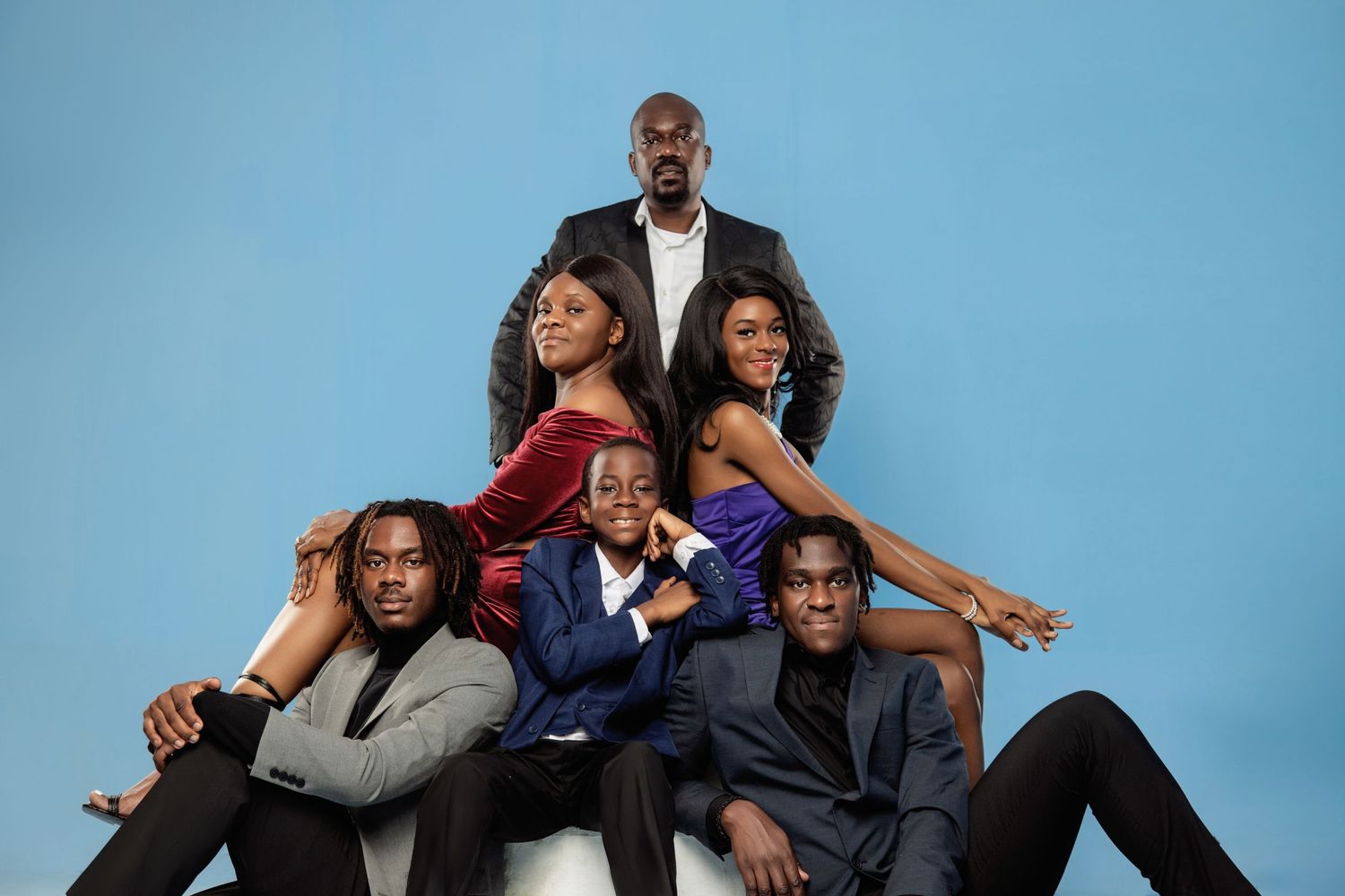 A group of friends pose together playfully on a blue background in a series of connected photos.