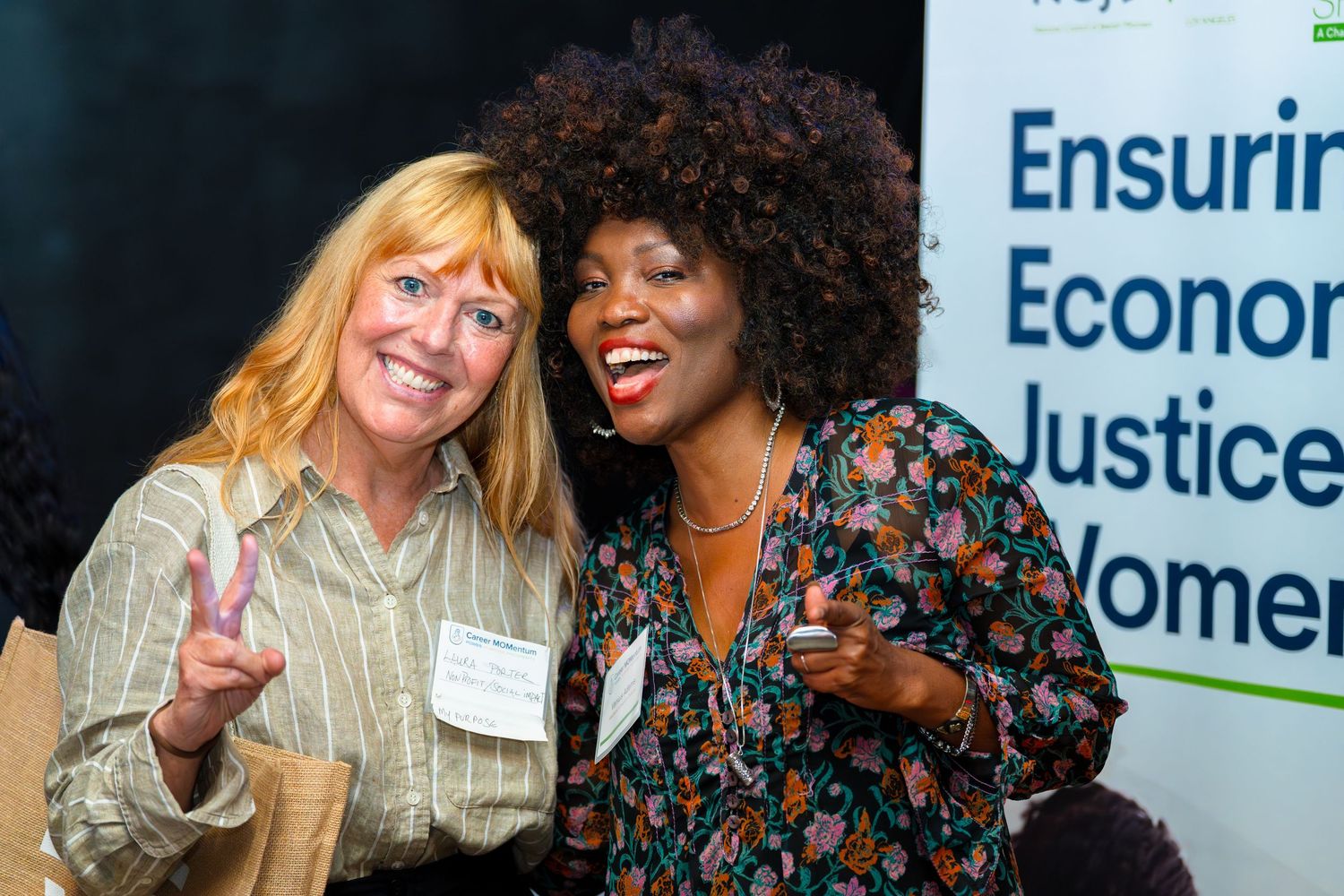 Two attendees sharing a joyful moment at a women's economic justice event.