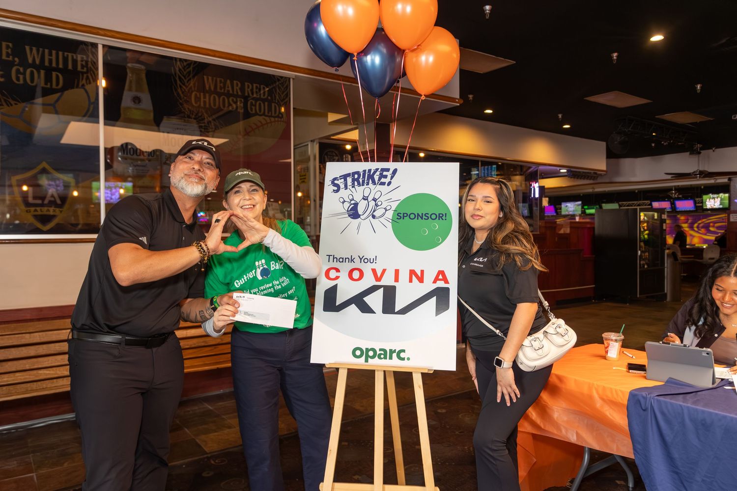 Corporate event space decorated with orange balloons and KIA branding displays.