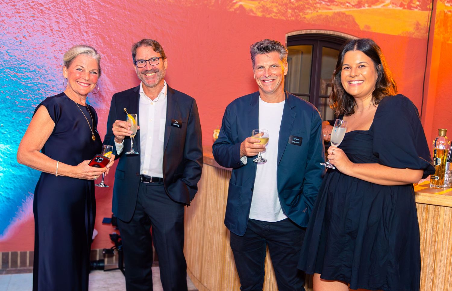 Professional group in formal attire posing at an evening event with colorful lighting.