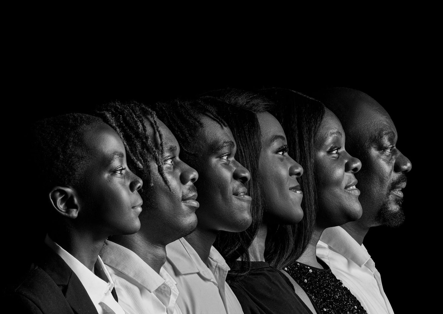 Black and white photo of people in a row looking up at the same angle, creating a dramatic silhouette effect.