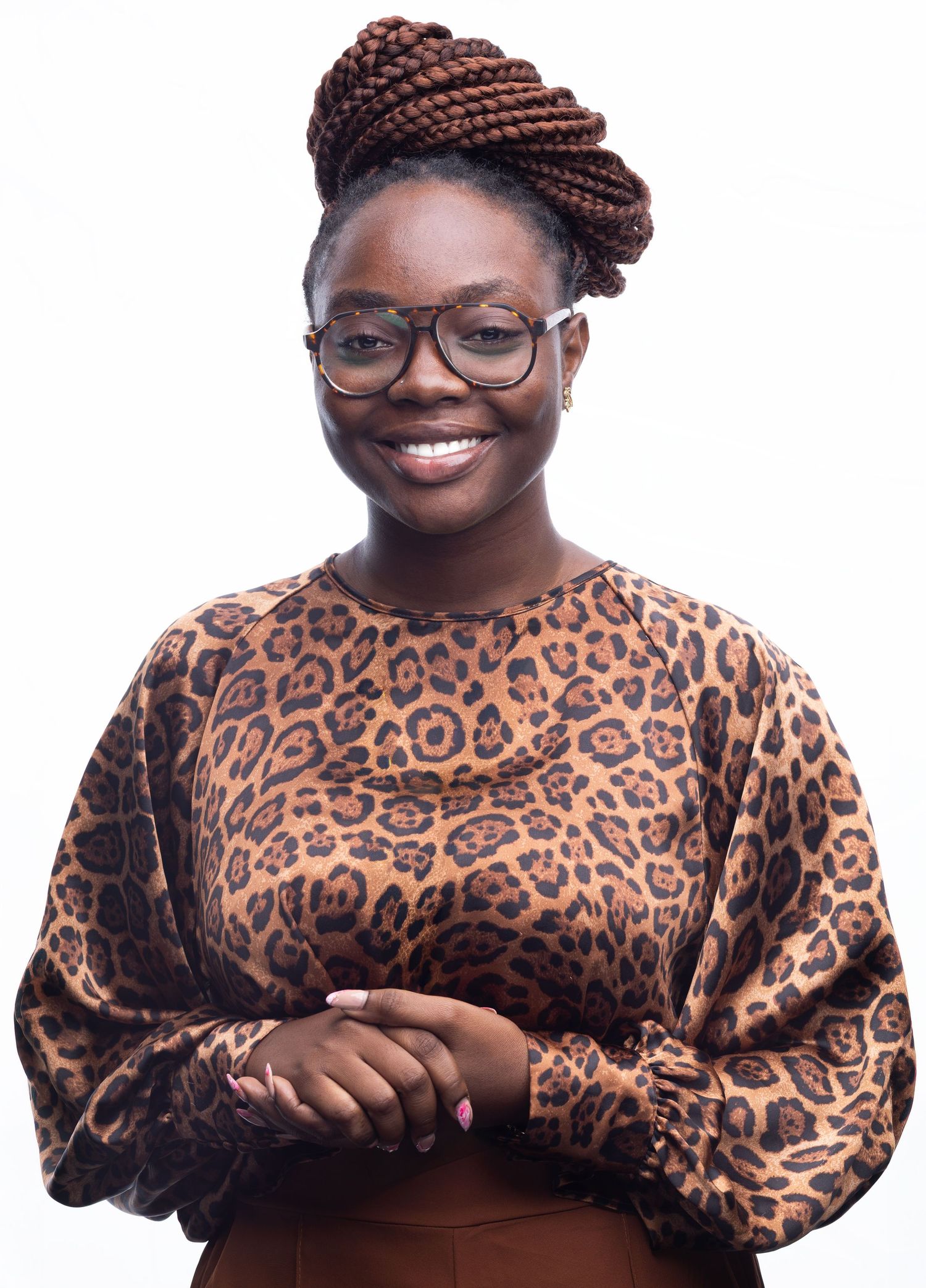 A person wearing glasses and a leopard print top smiles warmly against a white background.