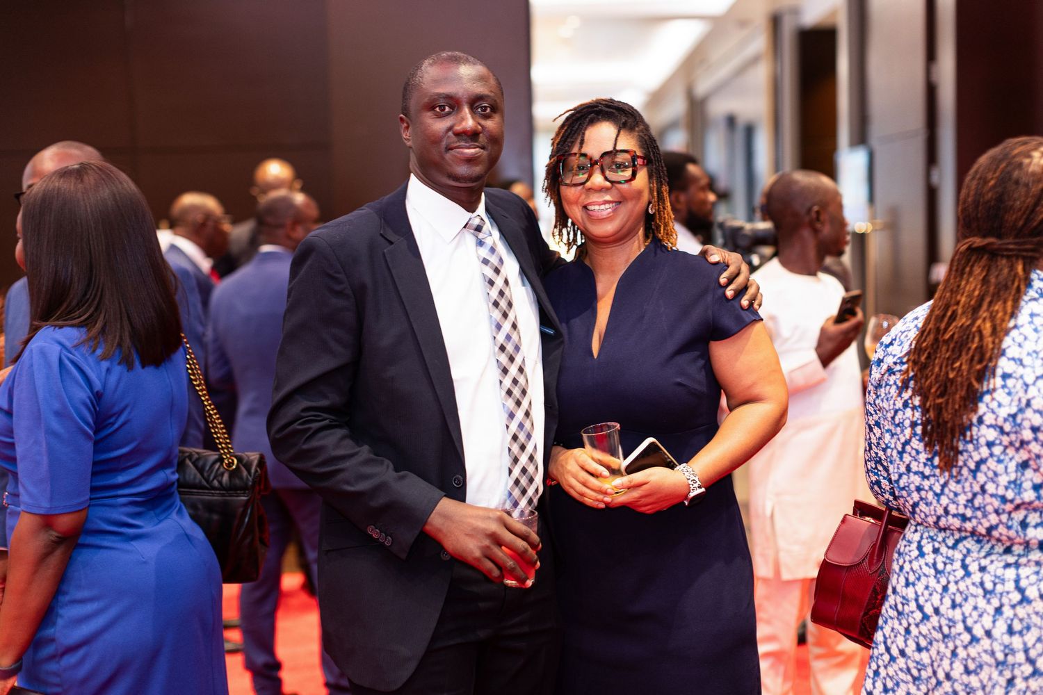 A diverse group of formally dressed people mingle and socialize at an indoor networking event.