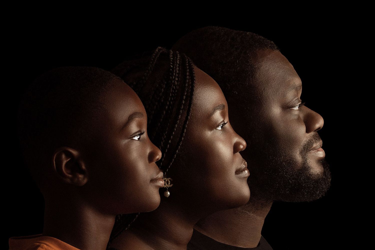 Artistic profile portraits of three people with dramatic side lighting against dark background.