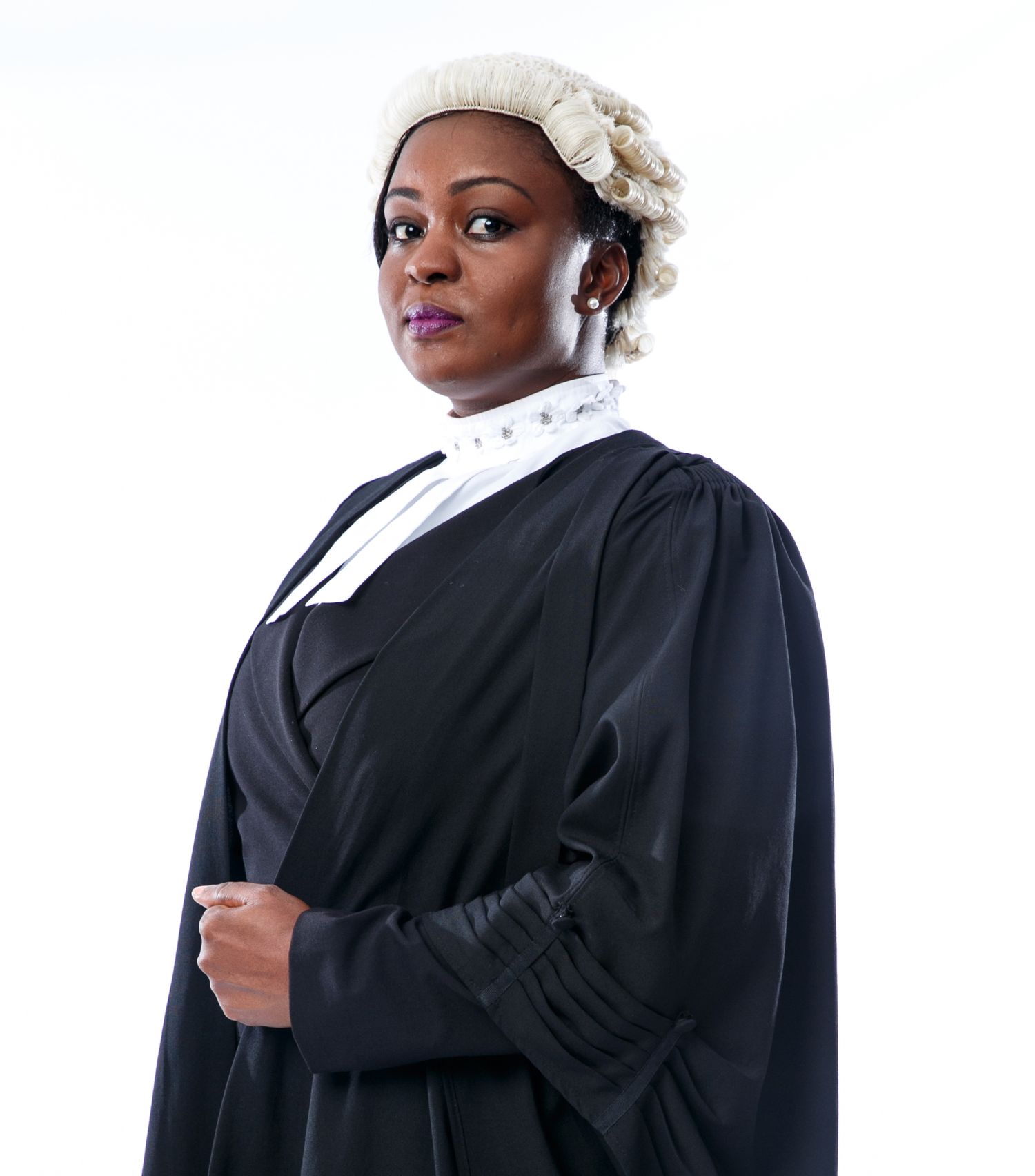 Legal professional wearing traditional black barrister robe with white collar and white floral hair accessory.