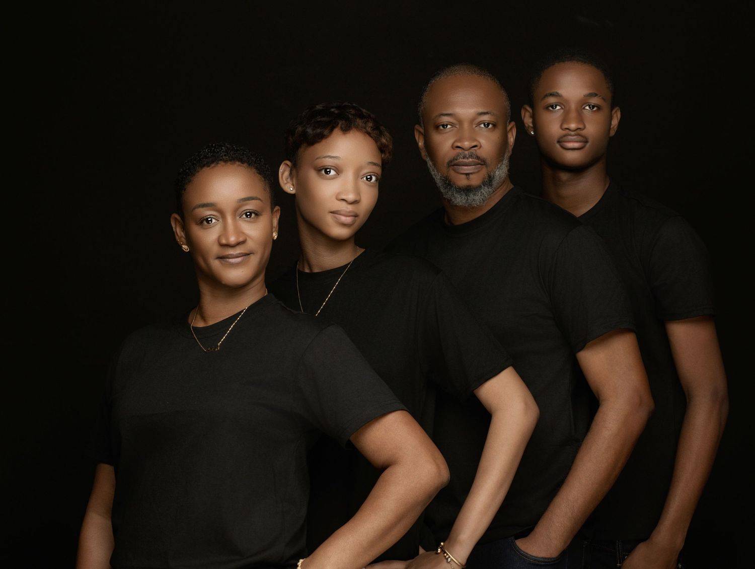 A group of people wearing black clothing pose together against a dark background for a portrait.