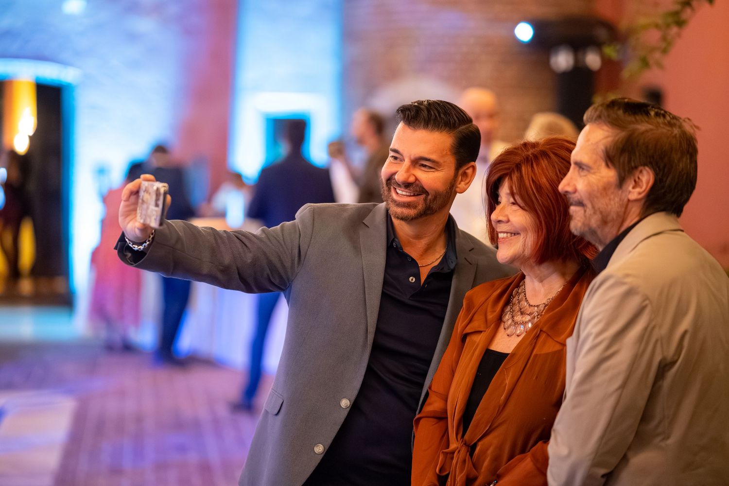 Group of people socializing at an evening event with blue and orange ambient lighting.