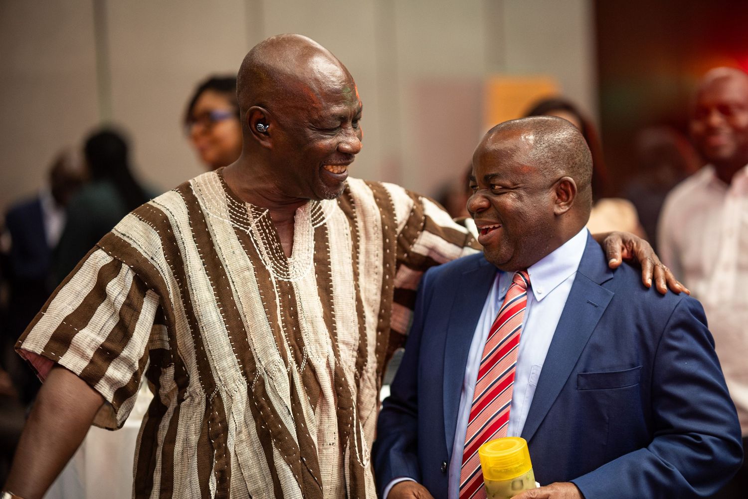 A sequence of photos showing two men in formal attire sharing laughs and conversations during an event.