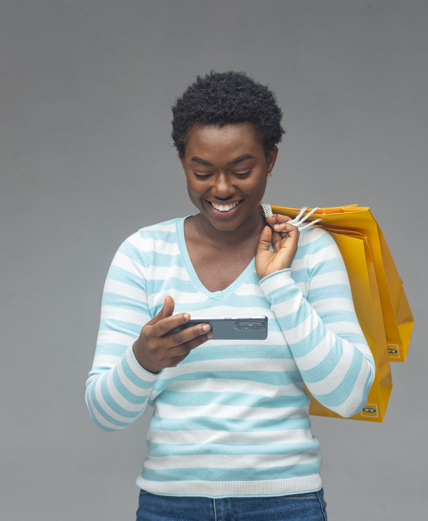 Person in striped sweater smiling while looking at mobile device.
