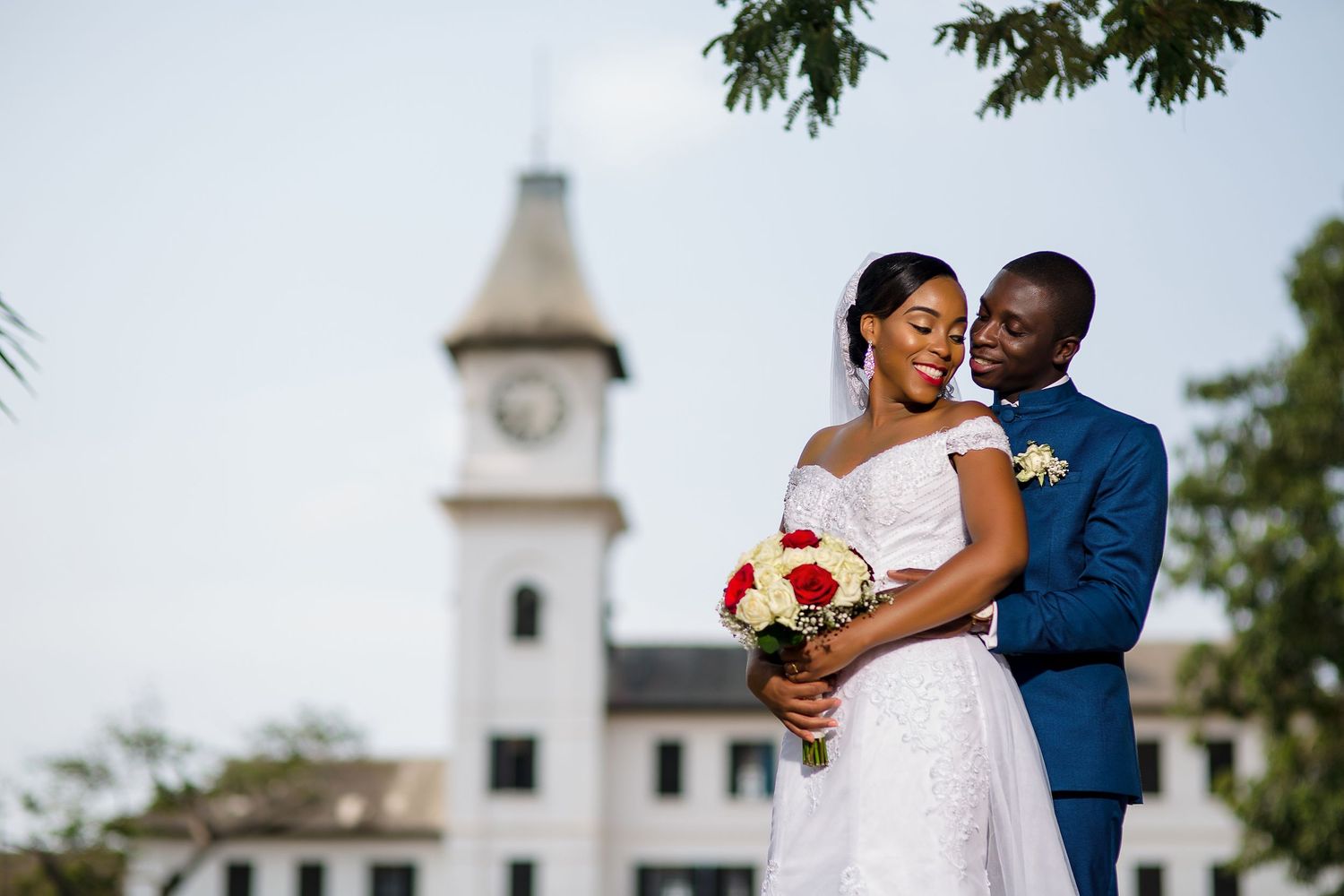 A romantic wedding couple shares a tender moment in front of a clock tower on their special day.