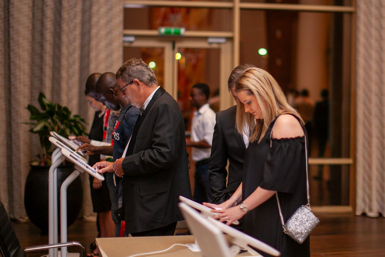 Guests in formal attire checking in at a registration desk during an elegant evening event.