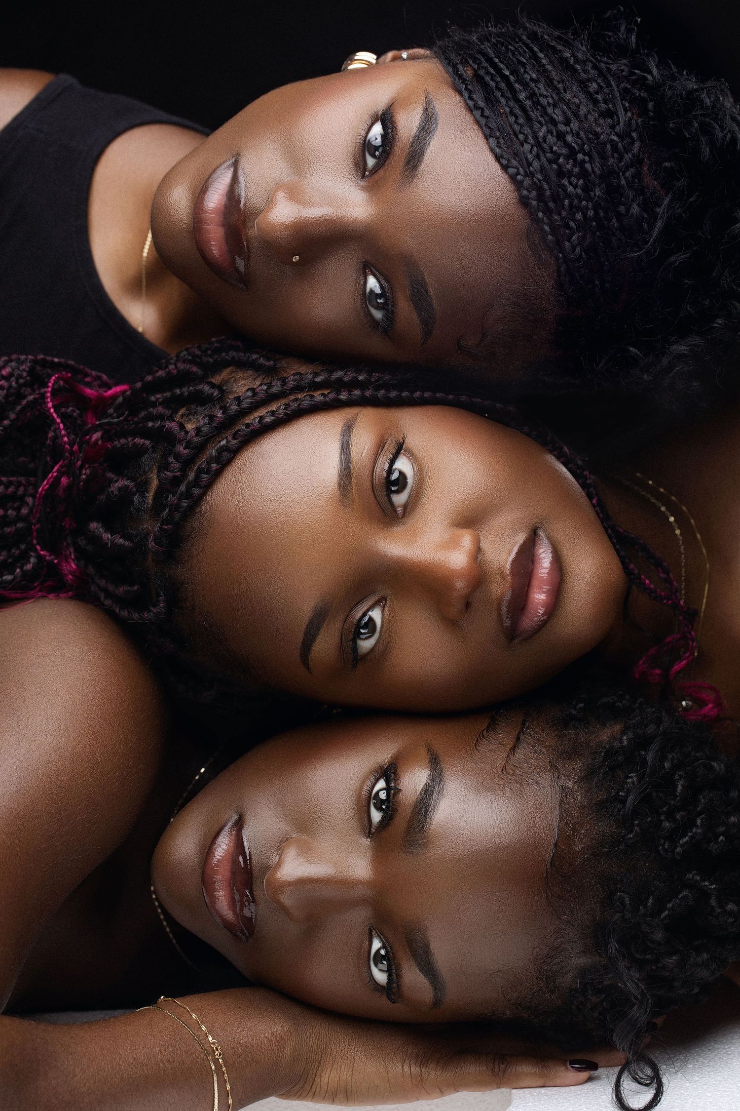 Intimate beauty portraits with braided hair styled against black backdrop.