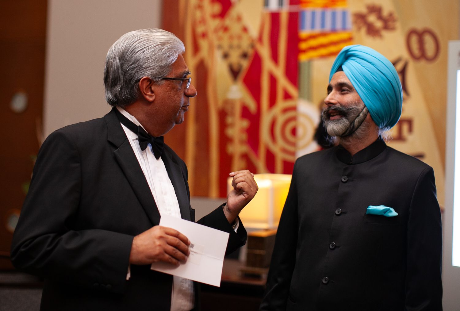 Two people in formal attire engage in conversation during what appears to be a diplomatic meeting.