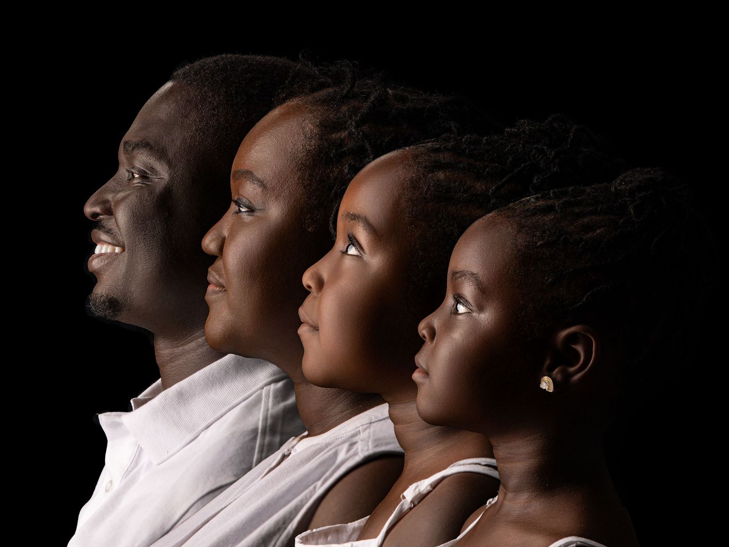Side profile view of four people in white shirts looking upward against dark background.