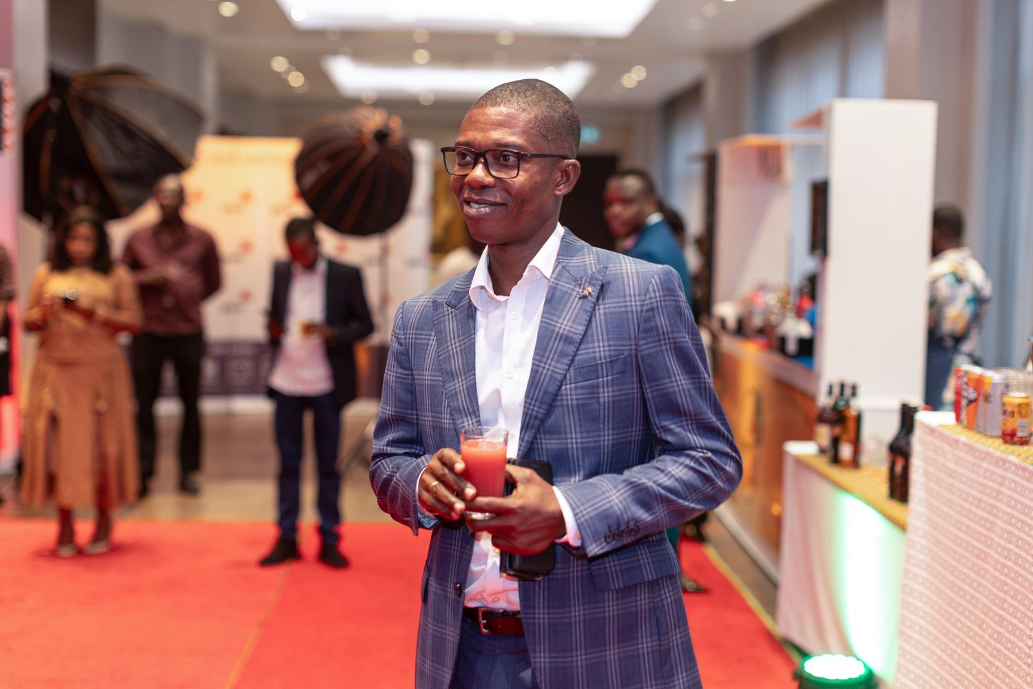 Professional networking event shows attendees in business attire mingling in a modern conference space.