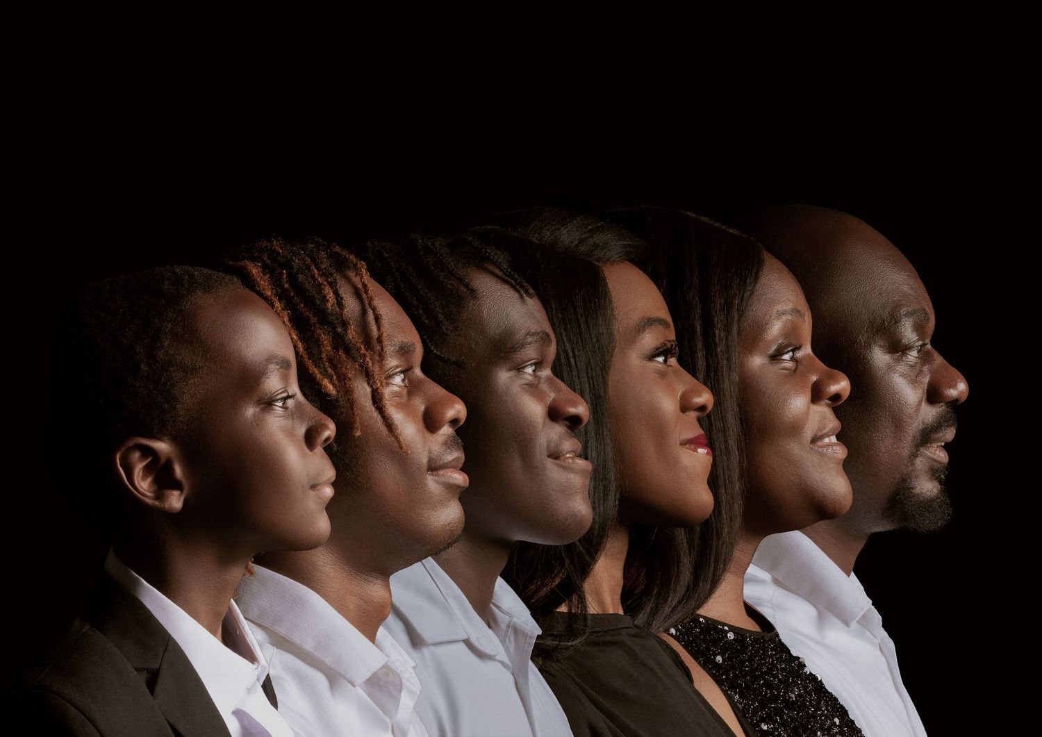 Side profile portrait of six people in white shirts against dark background arranged in ascending height order.