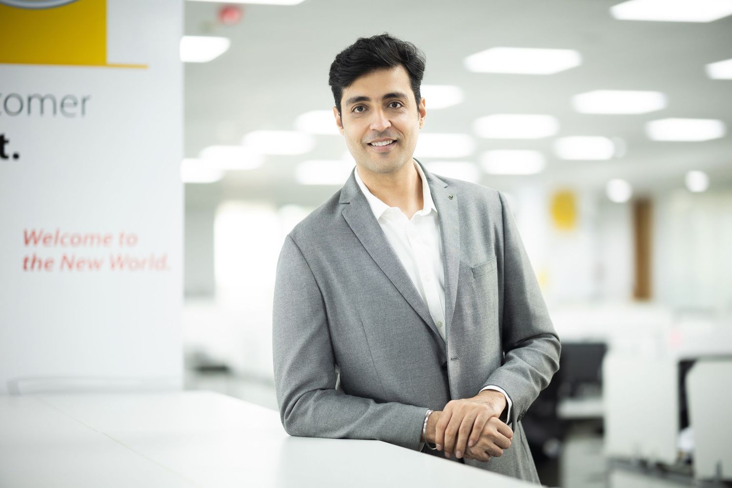 Businessman in grey suit standing in modern office space.