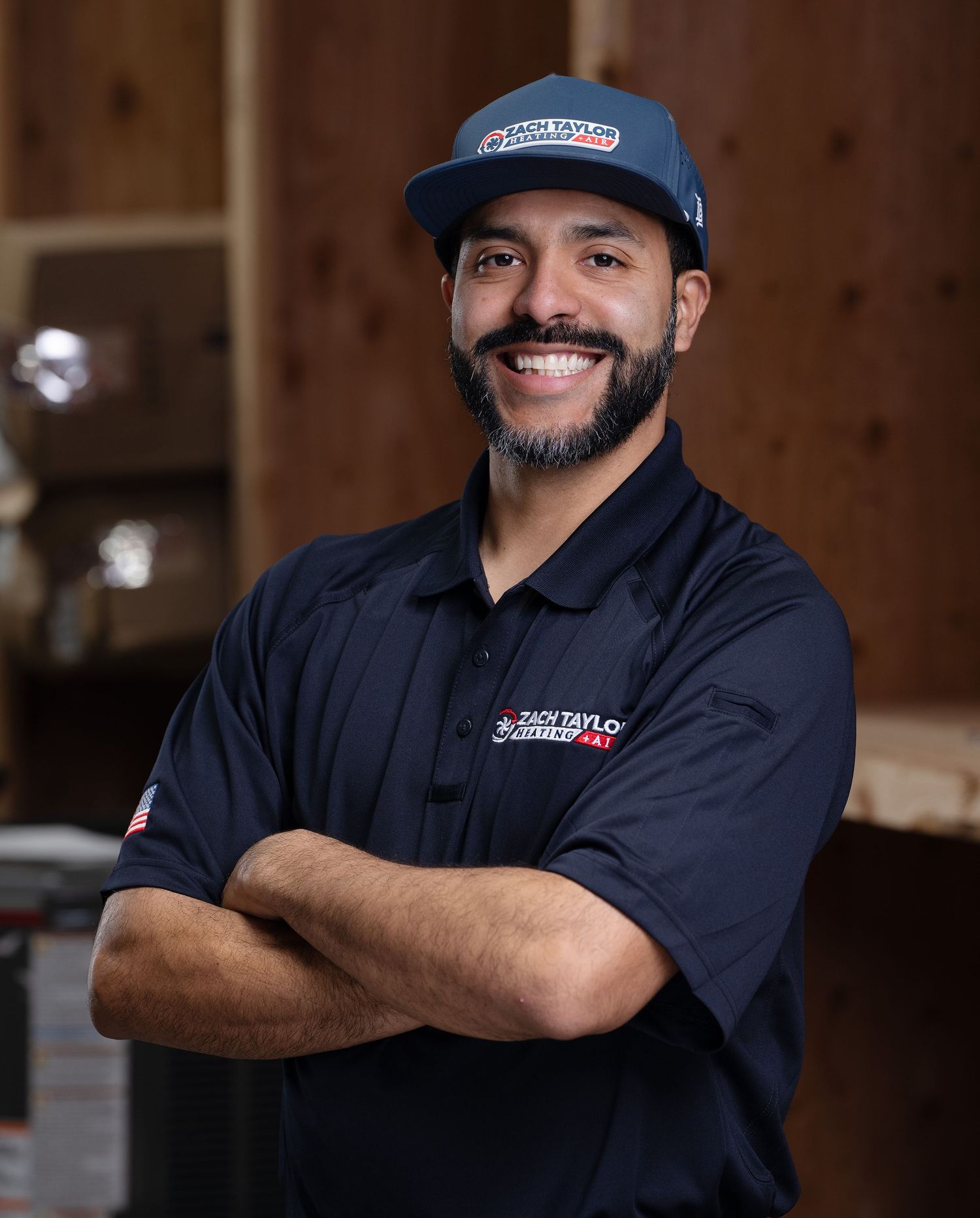 Professional service technician in navy blue uniform and cap smiling in workshop setting.