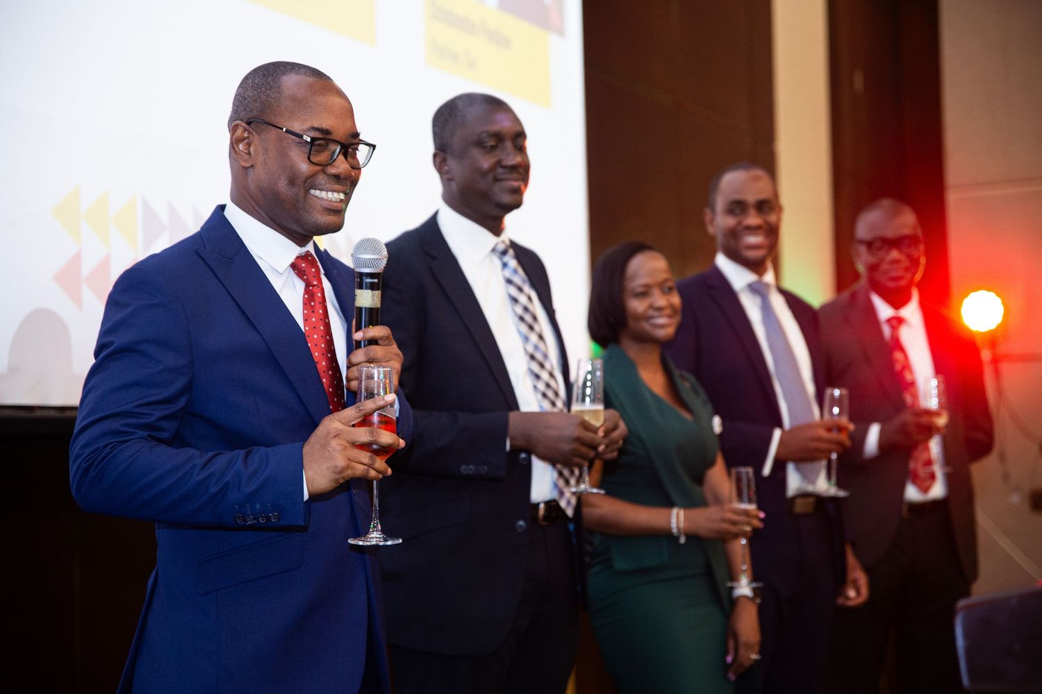 Business professionals holding wine glasses during networking reception in dimly lit venue.