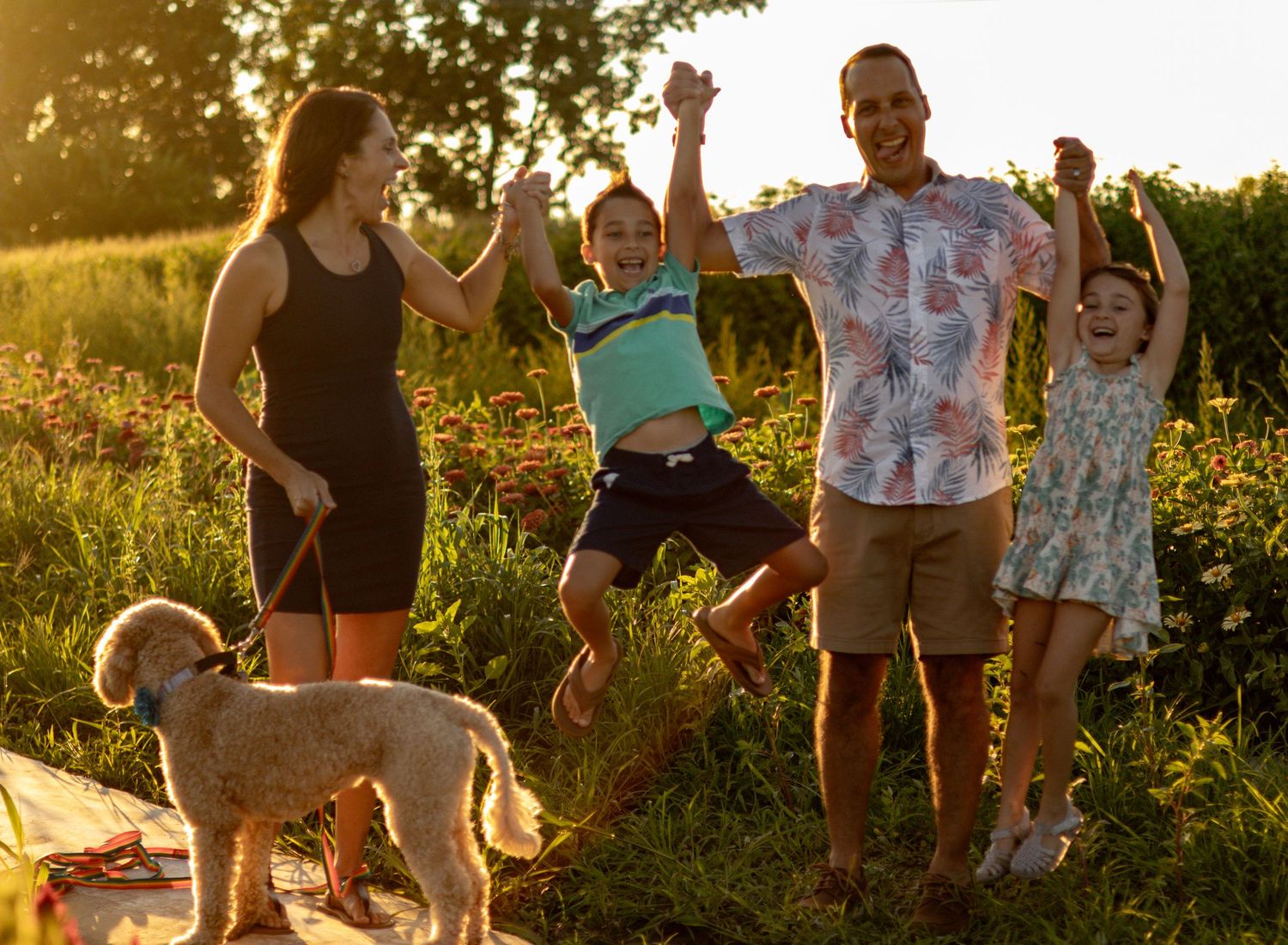 People gather outdoors in a sunny field during golden hour.